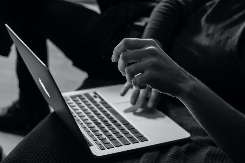 Grayscale Photo of Person Using MacBook to Record Video On Mac With External Camera